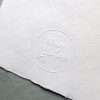 Raised impression embosser creating a subtle embossed design on white paper.