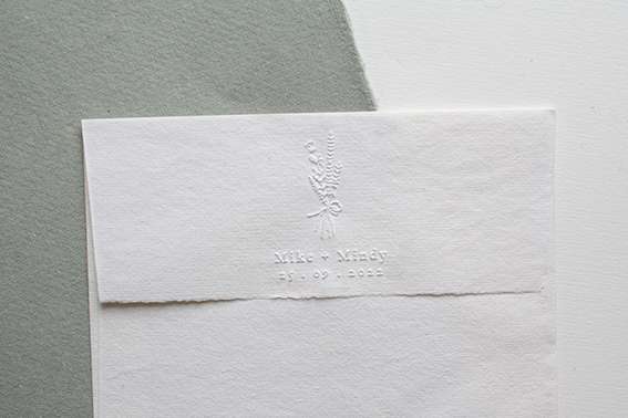 Rectangular paper embosser showing raised design on white sheet.
