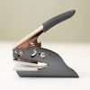 UK handheld embosser with rectangular die plate on beige background.