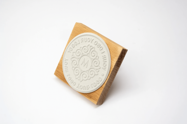 Wooden logo rubber stamp with engraved round design and handle.