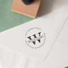 Circular address rubber stamp impression with wooden stamp beside it.