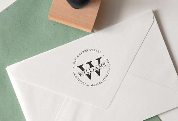 Circular address rubber stamp impression with wooden stamp beside it.