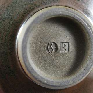 Round logo impression made using a rubber stamp pressed into clay.