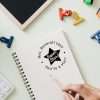 Teacher using custom classroom rubber stamp with star design on student paper.