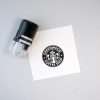 Round self-inking stamp beside a printed circular logo on white background.