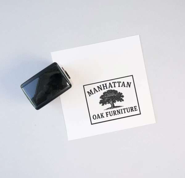 Signature self-inking stamp positioned next to a printed custom logo on white paper.